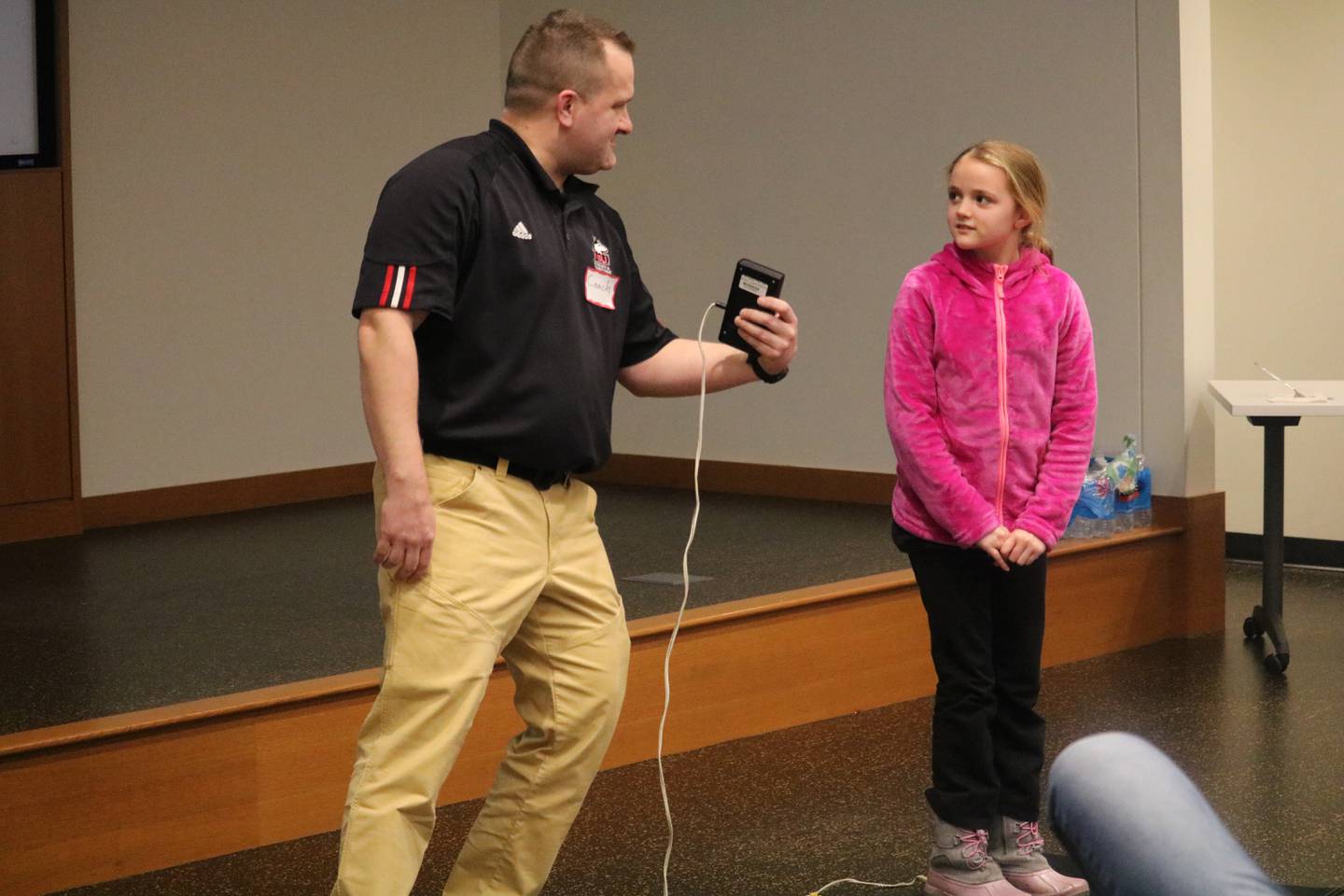NIU instructor Brandon Male (left) leads a demonstration with assistance from Kate Grych, 9, on how to use a jump mat during the Teens and Family  STEM Cafe, put on Jan. 12 at the DeKalb Public Library.
