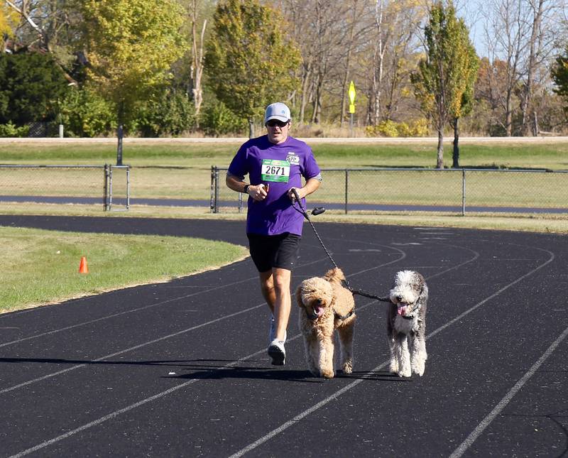 Jason Turner runs with his dogs Cabo and Winston in the Sugar Grove Park District’s inaugural Run to Remember 5K & Fun Run on Saturday, Oct. 19, 2024 in Sugar Grove.