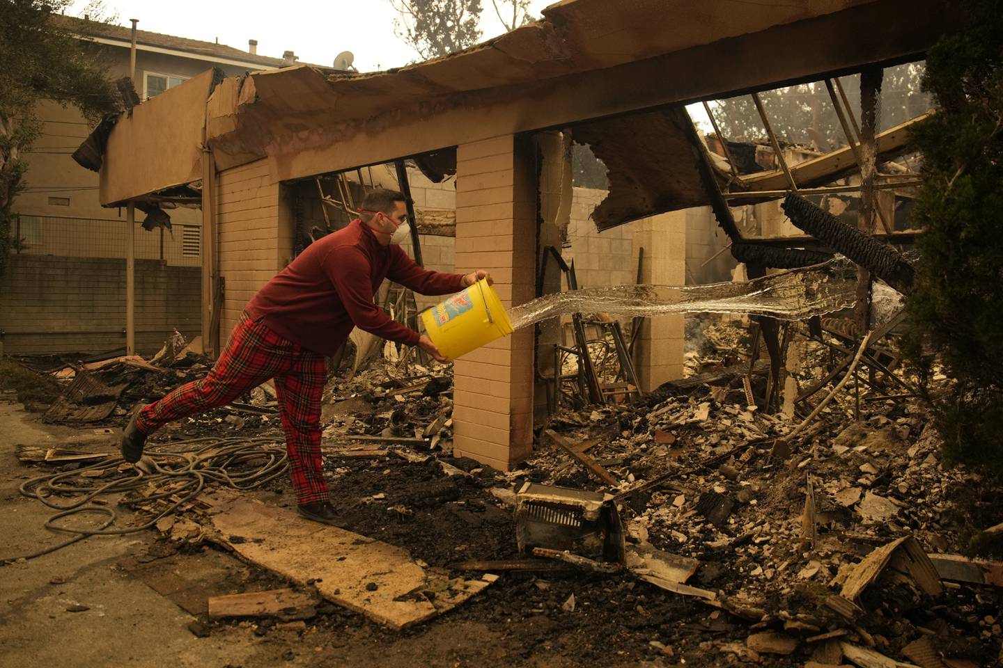 Shane Torre douses hot spots of what remains of his home In Altadena, Calif., Thursday, Jan. 9, 2025.