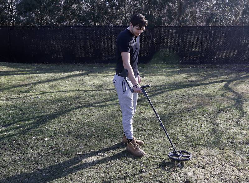 Darick Langos uses his metal detector to search the Fox River