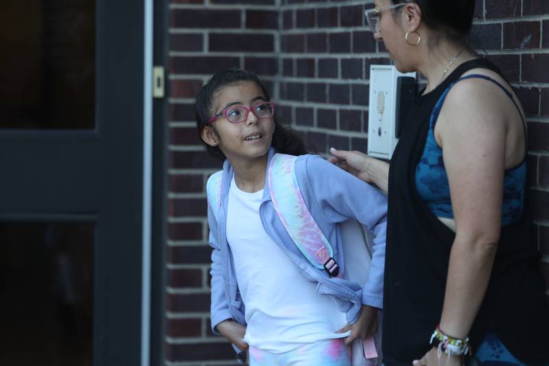 4th grader Camila Coronel stands with her step-mother Fanny Olmedo as she is one of the first students to arrive on the first day of school at Woodland Elementary School in Joliet. Wednesday, Aug. 17, 2022, in Joliet.