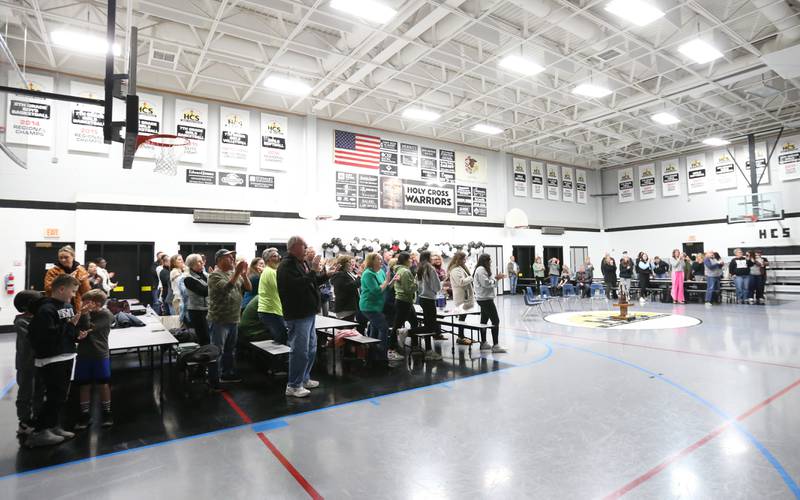 Fans stand and cheer on members of the Mendota Holy Cross eighth-grade boys basketball team during a reception reception on Tuesday, Feb. 20, 2024 at Holy Cross School. The team beat Pana Sacred Heart 41-33 to win the IESA Class 1A State championship.
