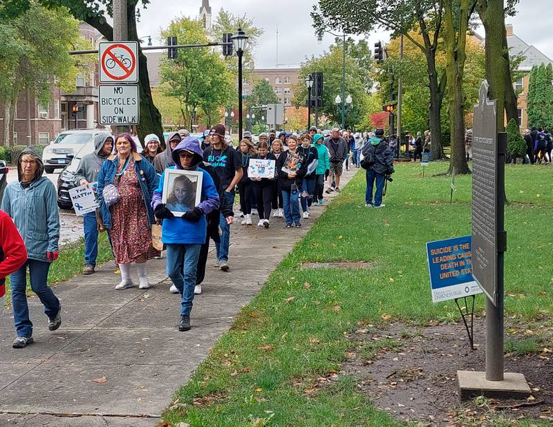 Walkers participated in the Out of the Darkness Walk on Saturday, Oct. 14, 2023, in Washington Square in Ottawa, holding signs and photos of loved ones who died of suicide to memorialize them.