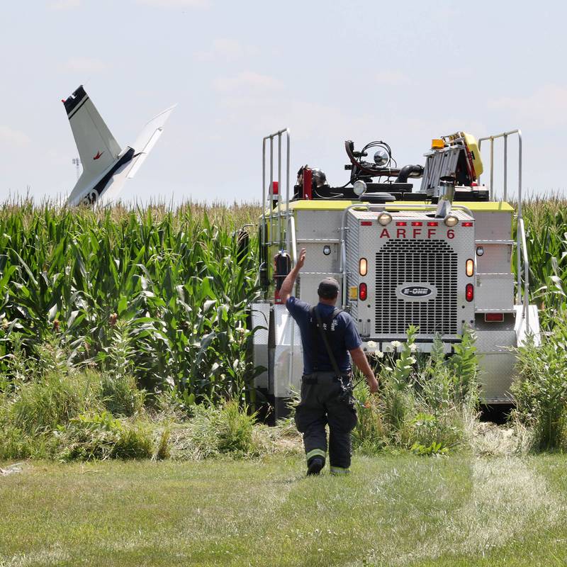 A DeKalb Fire Department vehicle exits the cornfield in front of the tail section of a crashed plane Thursday, July 27, 2023, behind a business at 260 West Lincoln Highway in Cortland.