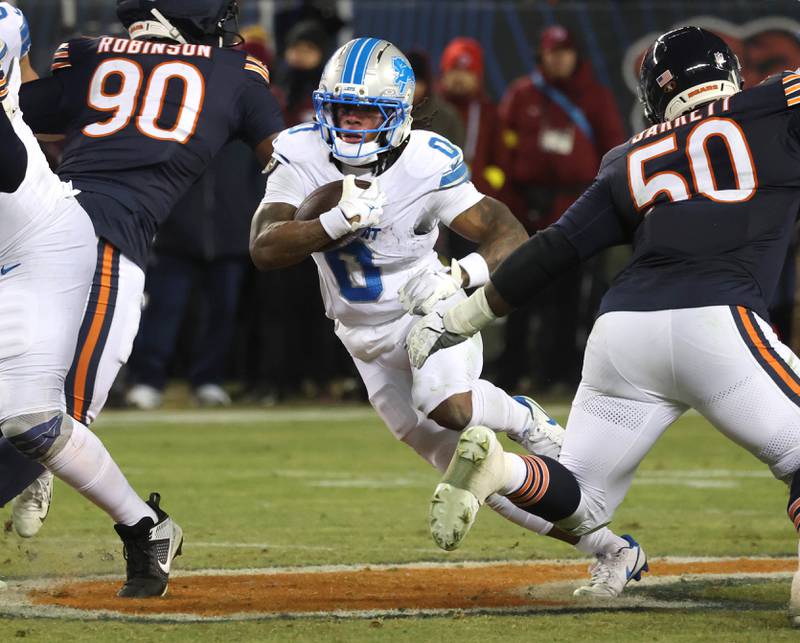 Detroit Lions running back Jahmyr Gibbs runs between Chicago Bears defensive end Dominique Robinson (left) and defensive end Grady Jarrett during their game Sunday, Jan. 4, 2026, at Soldier Field in Chicago.
