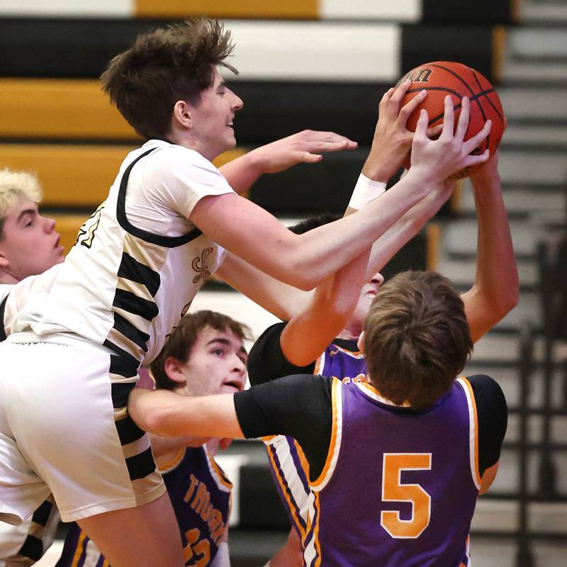 Sycamore's Ben Larry grabs a rebound over two Mendota defenders during their game Wednesday, Dec. 13, 2023, at Sycamore High School.