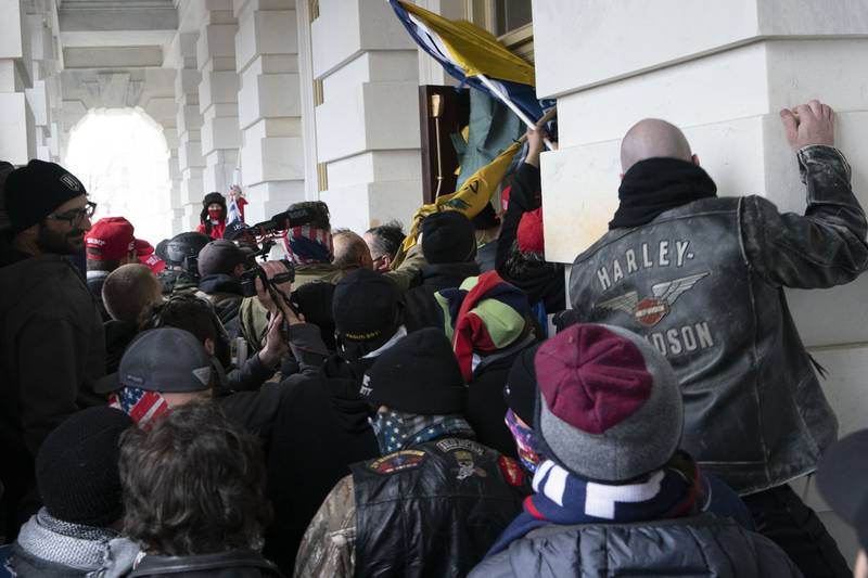 FILE - Insurrectionists loyal to President Donald Trump try to open a door of the U.S. Capitol as they riot in Washington, Jan. 6, 2021. Three active-duty Marines have been charged in the riot at the U.S. Capitol. Court records show that Micah Coomer, Joshua Abate and Dodge Dale Hellonen were arrested this week on misdemeanor charges after fellow Marines helped investigators identify them in footage among the pro-Trump mob on Jan. 6, 2021. (AP Photo/Jose Luis Magana, File)