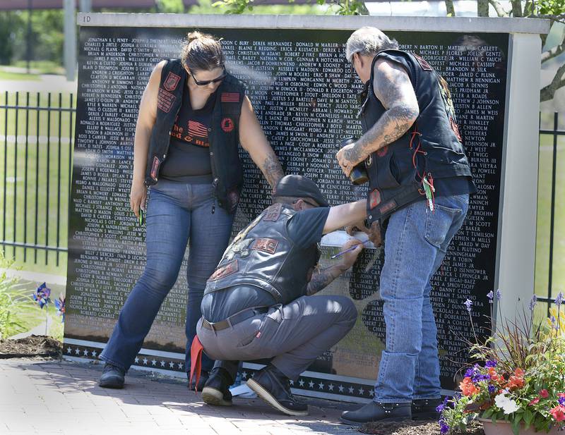 Some of those participating in the Annual Illinois Motorcycle Freedom Run, copy names of loved ones who lost their lives , that are etched on the Middle East Conflicts Wall Memorial Saturday during the Annual Illinois Motorcycle Freedom Run.