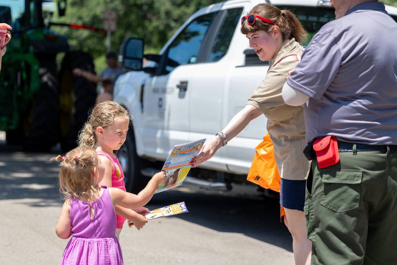 Kelli Ewbanka hands Sunny Gilbreth a book at the Touch a Truck event on Saturday, June 28, 2025 at Centennial Park in Peru.
