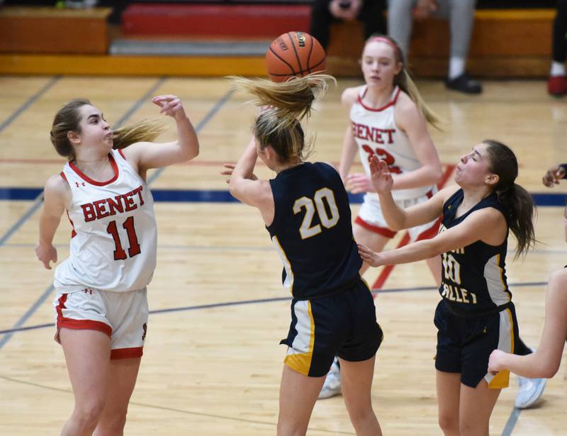 Benet's Sadie Sterbenz (11) swats at the ball while going for the rebound with Neuqua Valley's Kylee Norkus (20) and Zoe Navarro during Tuesday’s IHSA Class 4A regional semifinal girls basketball game in Aurora.