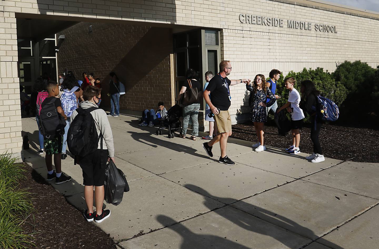 Dean of Students and physical education teacher Jason Laidig greats students as thy wait for the school doors to open Monday morning, August 15, 2022, during the first day of school at District 200’s Creekside Middle School. Many McHenry County area schools return to session this week.