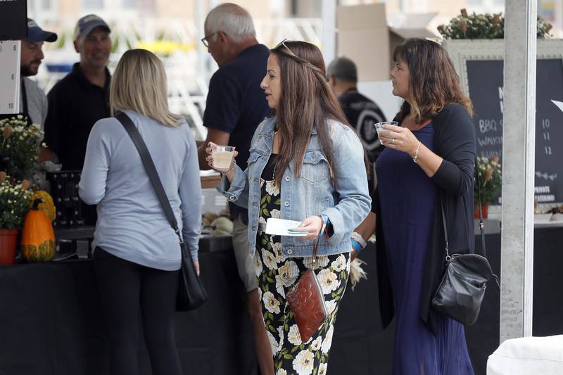 Valeska Chaidez, center, and Michelle Reaska, right, both of Aurora look over the food offerings as they enjoy a glass of wine at the Festival of the Vine Friday September 8, 2023 in Geneva.