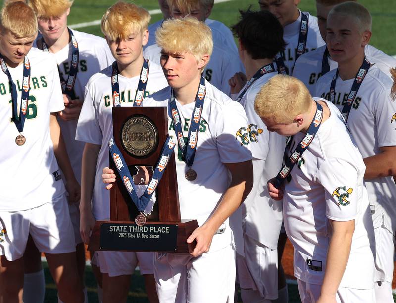 Coal City players collect their trophy Friday, Nov. 7, 2025, after their Class 1A state third place win over Chicago Academy at Hoffman Estates High School.