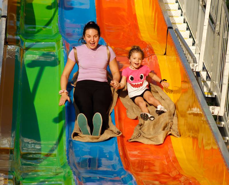 Nikola Stuart, from Downers Grove, laughs with her daughter Hailey while going down the slide at the Downers Grove Rotary GroveFest on Thursday, June 19, 2025.