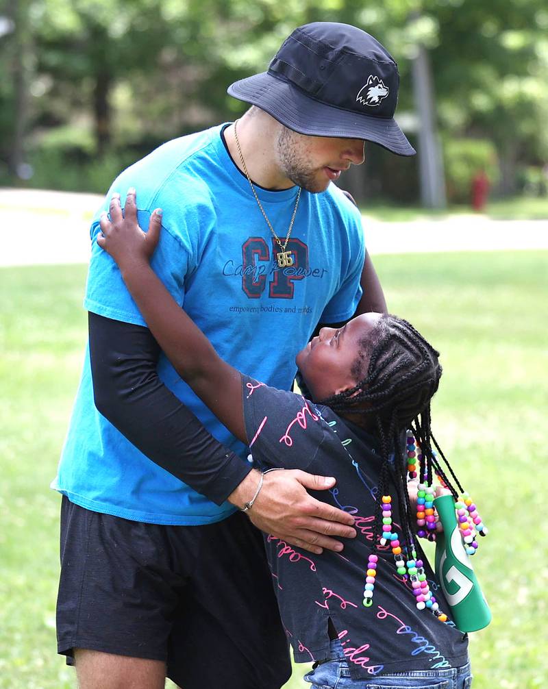 Trey Urwiler, a camp councilor at Camp Power gets a hug from participant Malania Sanders, 6, from DeKalb, Tuesday, July 18, 2023, at Welsh Park in DeKalb. Camp Power, which is run by the Kishwaukee Valley YMCA, is a summer program for youth at University Village that provides positive activities for kids.