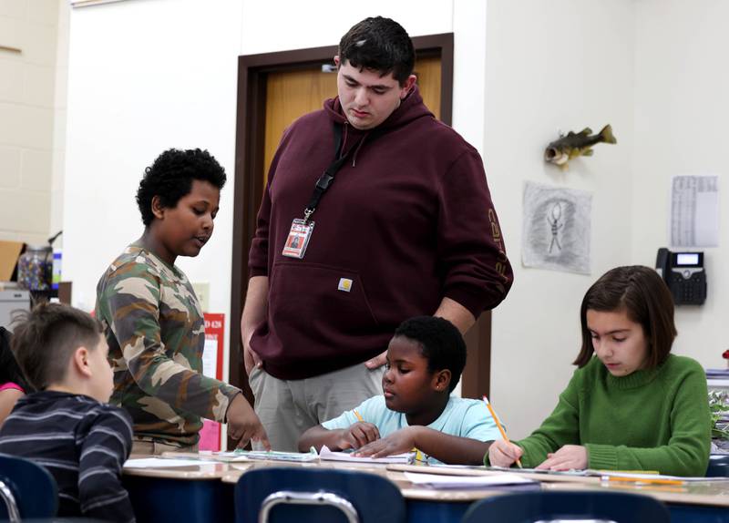 Drew Hoth, former Northern Illinois University football player and current student teacher in District 428, checks in with a group of students Thursday, March 20, 2025, at Jefferson Elementary School in DeKalb.