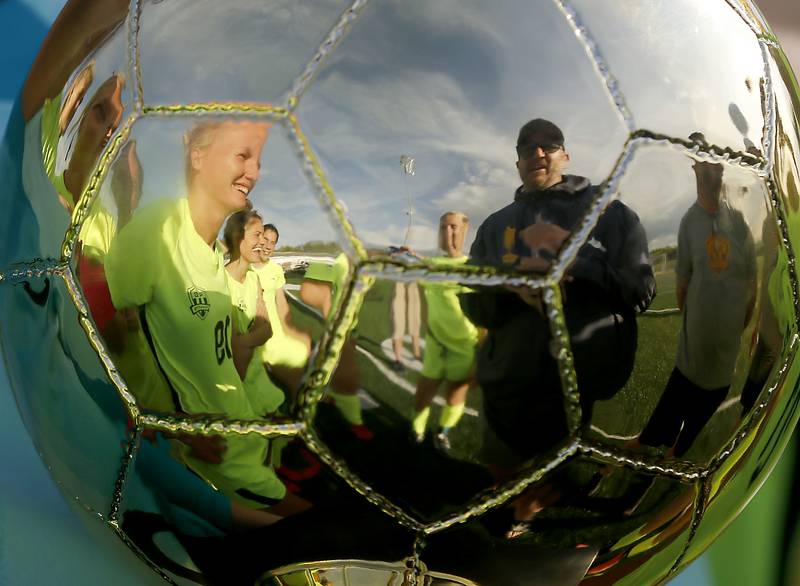 Richmond-Burton head coach Casey DeCaluwe (right) is reflected in the trophy as he talks to his team after they defeated Johnsburg 4-0 in the Kishwaukee River Conference Girls Soccer Tournament Championship Match on Wednesday, May 1, 2024, at Richmond-Burton High School.