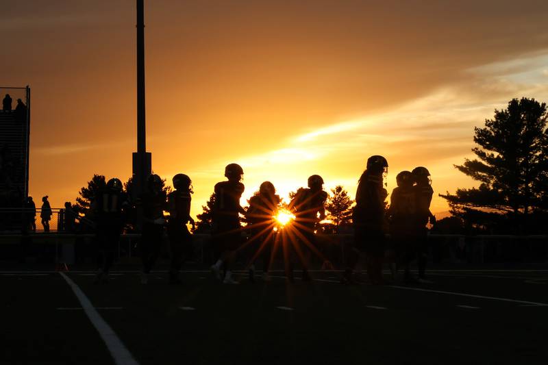 Herscher football players warm up ahead of the annual rivalry game against Bishop McNamara as the sun sets on Friday, Sept. 5, 2025. The Fightin' Irish would pull ahead to 45-28 victory over the Tigers in the fourth quarter.