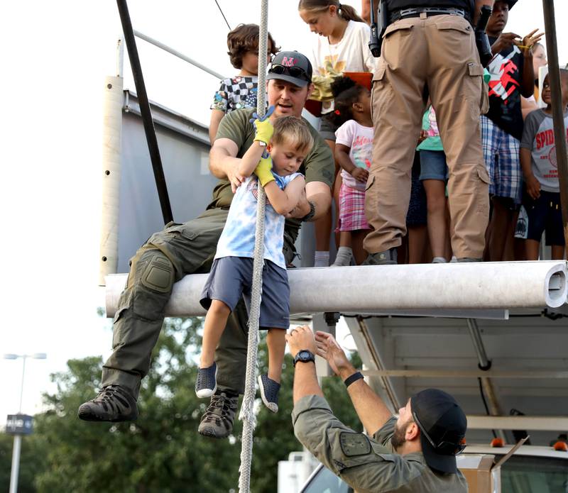 Trey Sronskoski, 4, of Geneva is helped on a rope by Evan Darger (top) and Joe Gaske (bottom) during the Kane County Sheriff’s Office National Night Out event in St. Charles on Tuesday, Aug. 1, 2023. The community-building event began nationally in 1984.