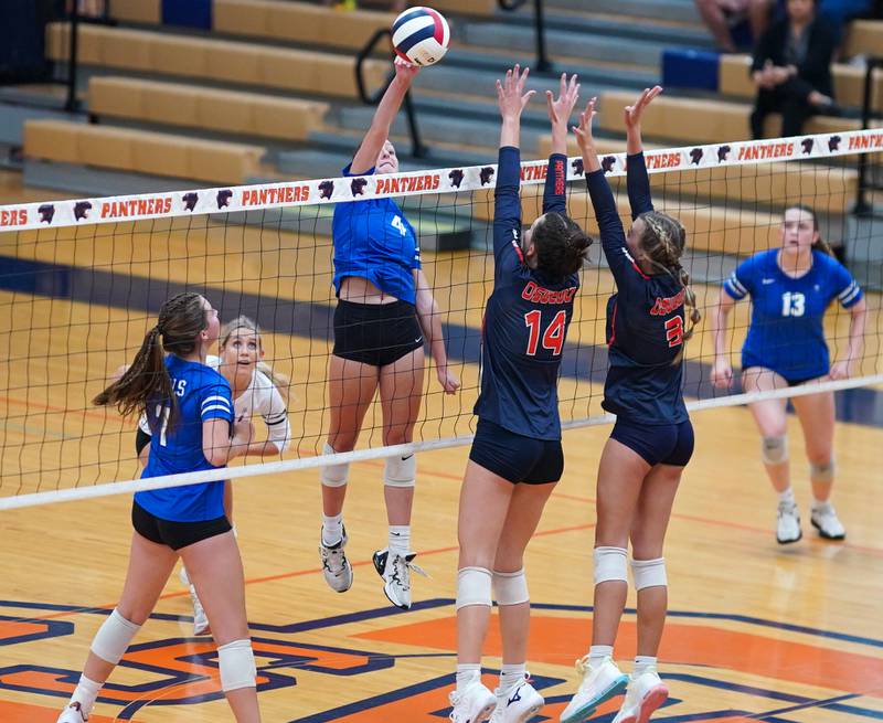 Rosary’s Reese Gilla (4) goes up for a kill against Oswego’s Mia Jurkovic (14) and Riley Borrowman (3) during a volleyball match at Oswego High School on Tuesday, Aug 29, 2023.
