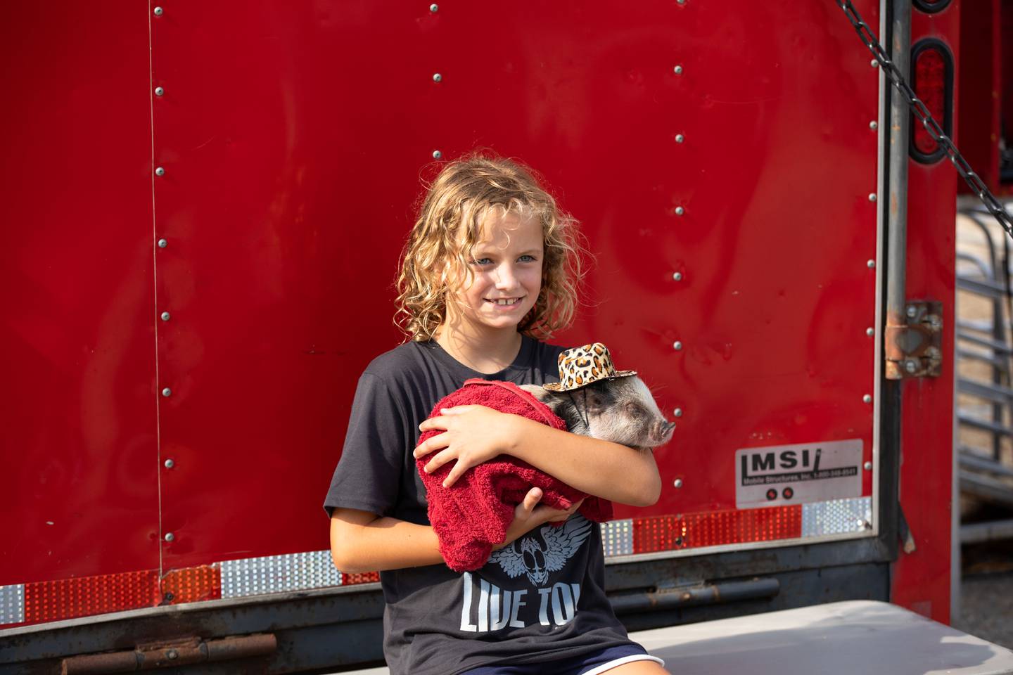 Mia Bachenberg, 9, of South Elgin poses for a picture with a piglet during the last day of the Kane County Fair on Sunday, July 17, 2022.