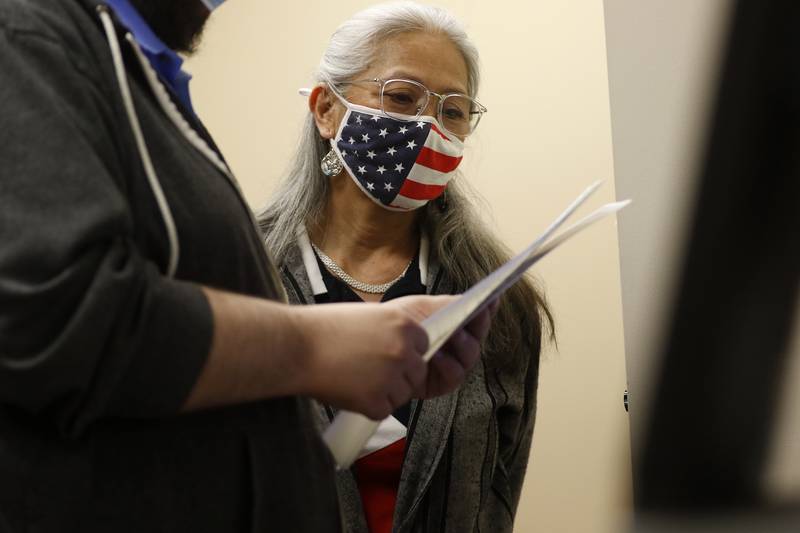 Election judge Anna Brettman of Huntley watches as McHenry County information technology resource employee A.J. Degenhardt feed ballots into a tabulation machine inside the voting tabulation room at the McHenry County Administrative Building on Thursday, April 8, 2021, in Woodstock.