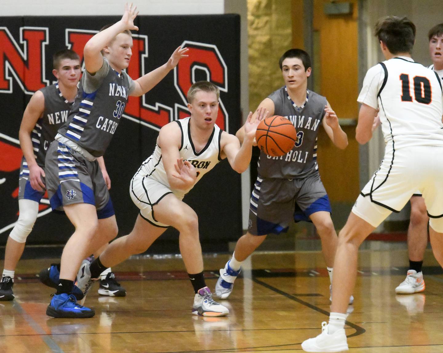 Byron's Braylon Kilduff passes the ball out of the lane as Newman's Cody McBride, Sax Snyder, and Garret Matznick defend during the championship game of the 62nd Forreston Holiday Tournament on Thursday, Dec. 21, 2023.