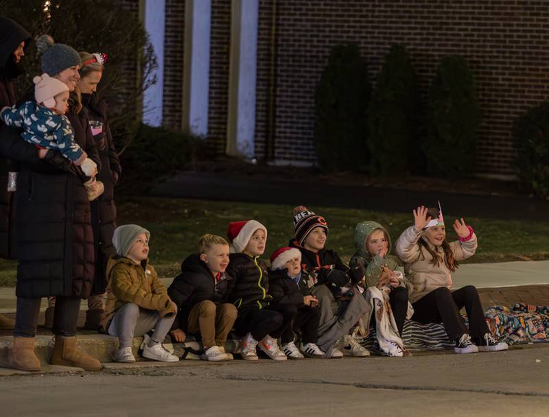 Children wave and watch the floats drive down Cass Avenue during the annual Holly Days Frosty & Friends Parade in Westmont on Saturday, December. 7, 2024.