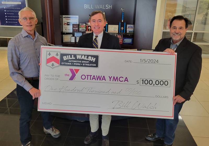 Bill Walsh, Jr. (center), the manager of the Bill Walsh Automotive Group, presents a symbolic check for $100,000 to YMCA executive director Joe Capese (right) and Y board treasurer Phil Devermann.
