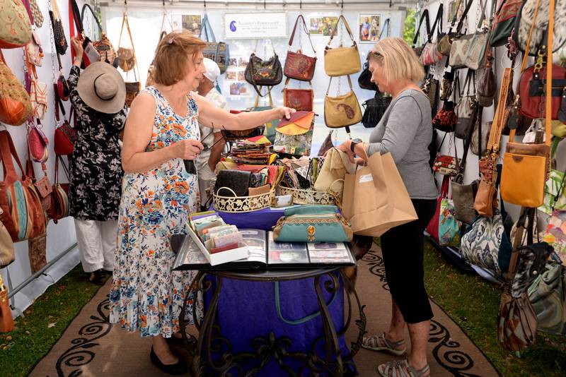 Sandra Venturoni (left) and Ginny Stein of Glen Ellyn look at hand made handbags and purses during the Glen Ellyn Art Festival on Sunday, Aug 24, 2024 at Lake Ellyn.