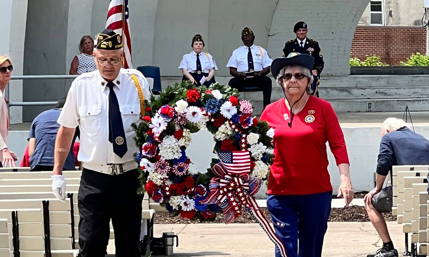 A member of the Sterling Legion Post 296 color guard escorts Karen Cowley as she walks to lay a wreath to honor fallen soldiers during Memorial Day services on Monday at Grandon Civic Center in Sterling.