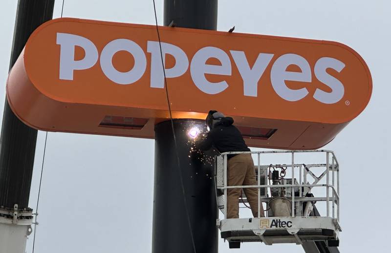A worker welds a large Popeyes sign in place for the new location near the intersection of May Road and Trompeter Road on Tuesday, Dec. 3, 2024 in Peru.