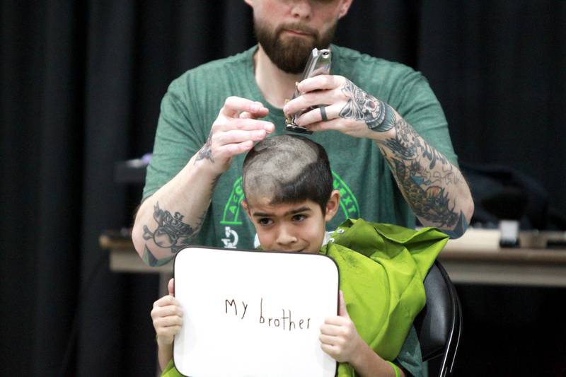 Ben Gonzalez, 8, has his head shaved by Dan Forni during the St. Charles Challenge fundraiser for the St. Baldrick’s Foundation on Friday, March 15, 2024 at St. Charles East High School.