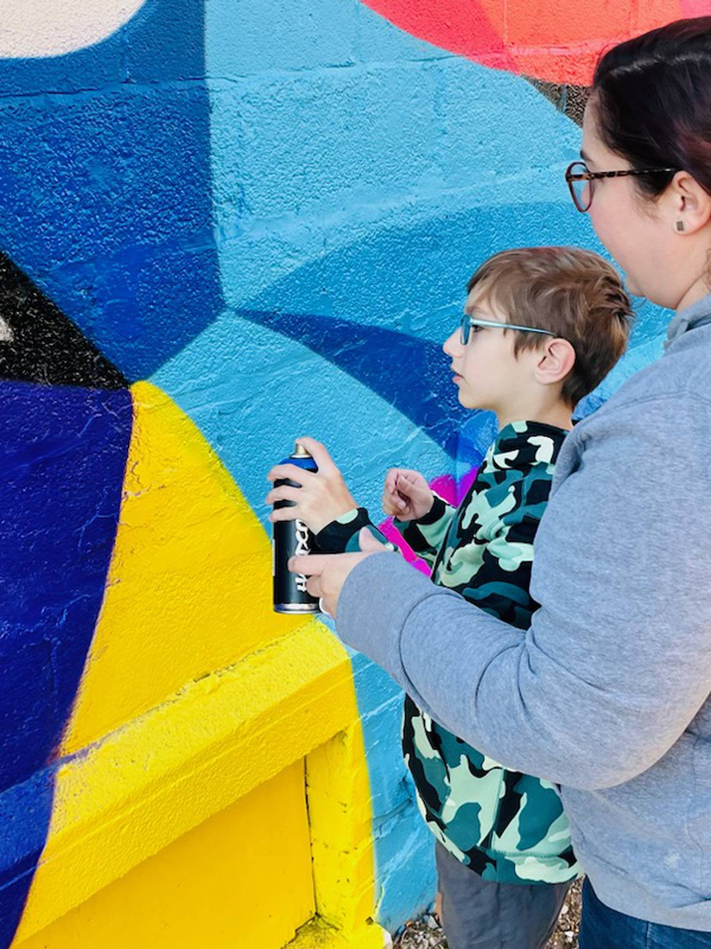 Elizabeth and Adam Pfeifer take their turns adding spray paint to McHenry's new mural on Saturday, Oct. 22, 2022, at 1216 Green Street. The artist outlined spots first, then invited volunteers to add paint in those areas.