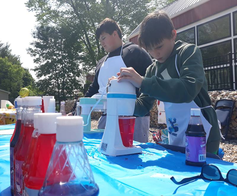 Waltham fifth grader Gabe Pawlak (right) prepares a snow cone for a customer Saturday, May 20, 2023, with business partner Brady Holland during Lemonade Day sponsored by the Illinois Valley Area Chamber of Commerce.
