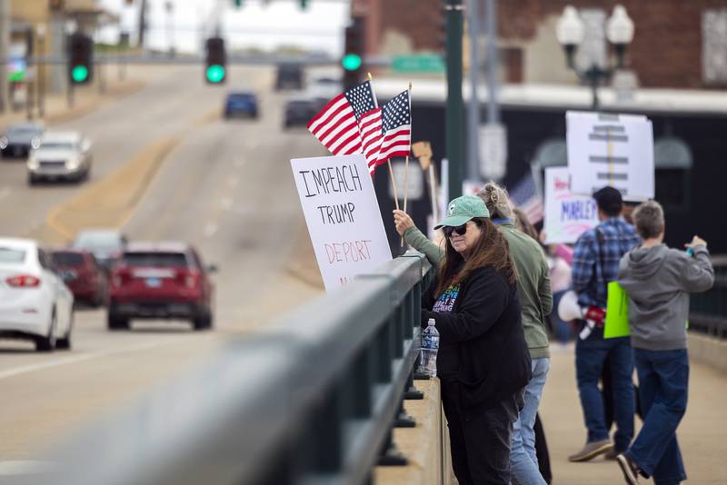 Kathleen Heitzler of Dixon displays a sign along the Galena Avenue bridge in Dixon Saturday, April 19, 2025, during a Hands Off rally protesting President Trump.