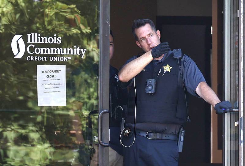 DeKalb police officers look out the door of the Illinois Community Credit Union Wednesday, July 31, 2024, as they investigate a morning bank robbery in the facility at 1500 Barber Greene Road in DeKalb.