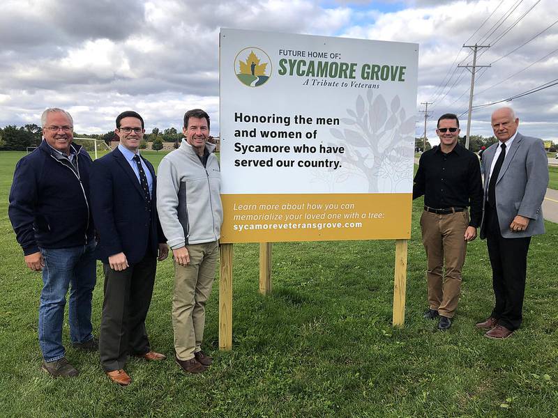 A local group led by Sycamore Mayor Curt Lang is working to create a new tribute to veterans along Route 23 called Sycamore Grove. The plan is to raise private donations and plant hardwood trees to honor those who have served. Pictured standing with the sign announcing the project are (left to right) Sycamore Park District board President Bill Kroeger, District 427 school board member Eric Jones, Dave Dozier of Sycamore (U.S. Army, retired), District 427 school board member Jeff Jacobson, and Lang.