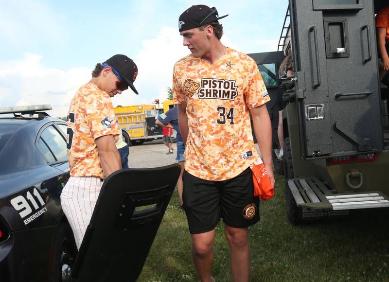 Illinois Valley Pistol Shrimp's Colin Horneman and Conner Prahl check out tactical gear during the Illinois Valley Pistol Shrimp First Responder Night on Tuesday, June 17, 2025 at Schweickert Stadium in Peru.