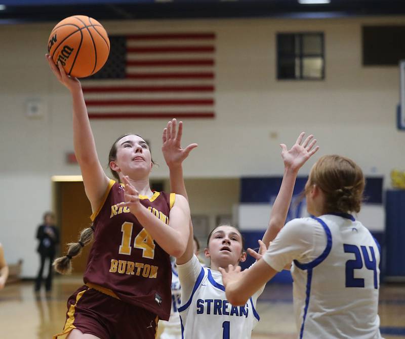 Richmond-Burton's Lilly Kwapniewski (left) drives to the basket agsisdnt Woodstock's Alex Nowacki (center) and Aiyana Fourdyce (right)during a Kishwaukee River Conference girls basketball game on Wednesday, Jan. 28, 2026, at Woodstock High School.