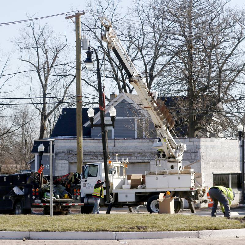 Workers use a crane to install a street light Tuesday Nov. 22, 2022, as workers put the finishing touches on the Woodstock roundabout at intersection of Lake Avenue and South and Madison streets. Construction on the roundabout near Woodstock's downtown is expected to wrap up this week, opening traffic and marking the end of several months of construction. The roundabout has been in the works for several years and was built out this year.