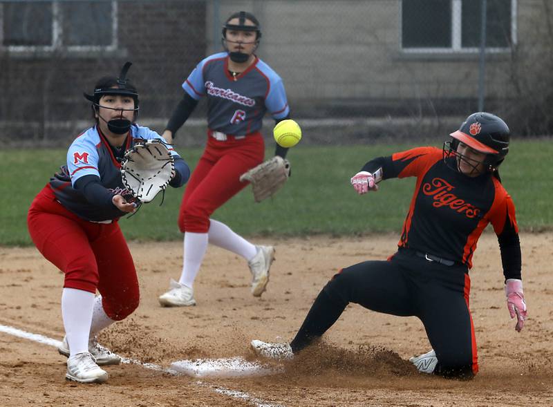Crystal Lake Central's Ella Arana slides into third base in front of the throw to Marian Central's Dianna Perez during a nonconference softball game on Thursday, April 3, 2025, at bates Park in Woodstock.