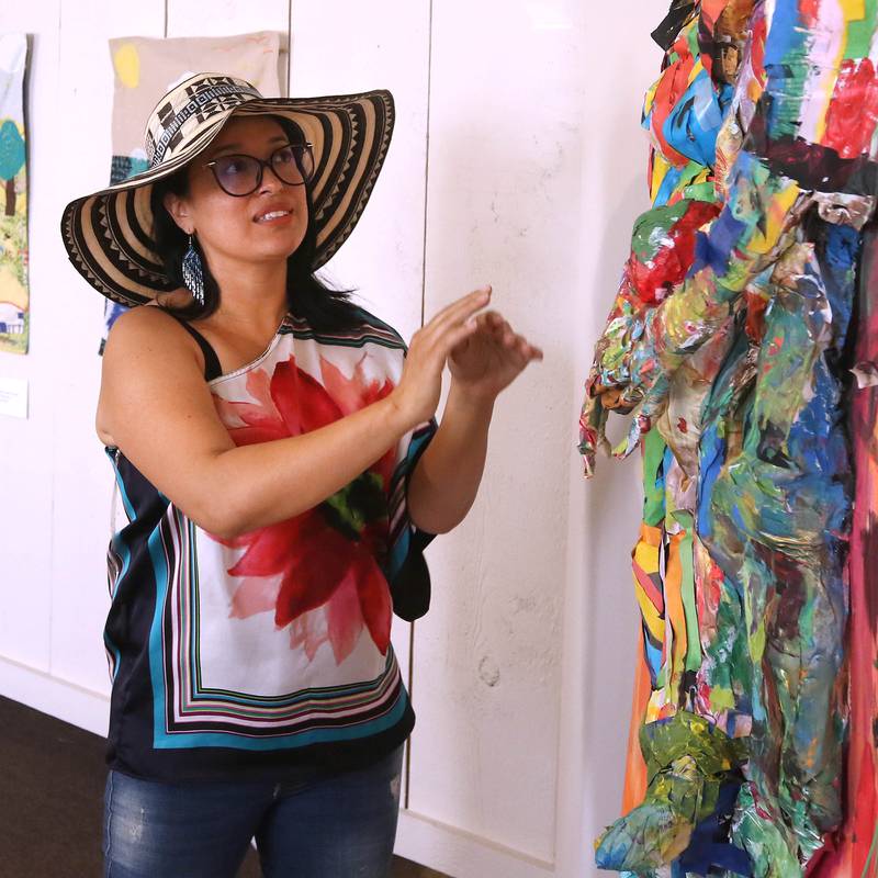 DeKalb resident Carolina Velandia talks about her work entitled “Dance, Love, and Art” Wednesday, Sept. 18, 2024, that is part of the Arts in Action exhibition at the Ellwood House Museum in DeKalb. The work behind her is by her mother Nohora S. Hernandez. The exhibit features work by local Latino artists and runs through the end of the year.