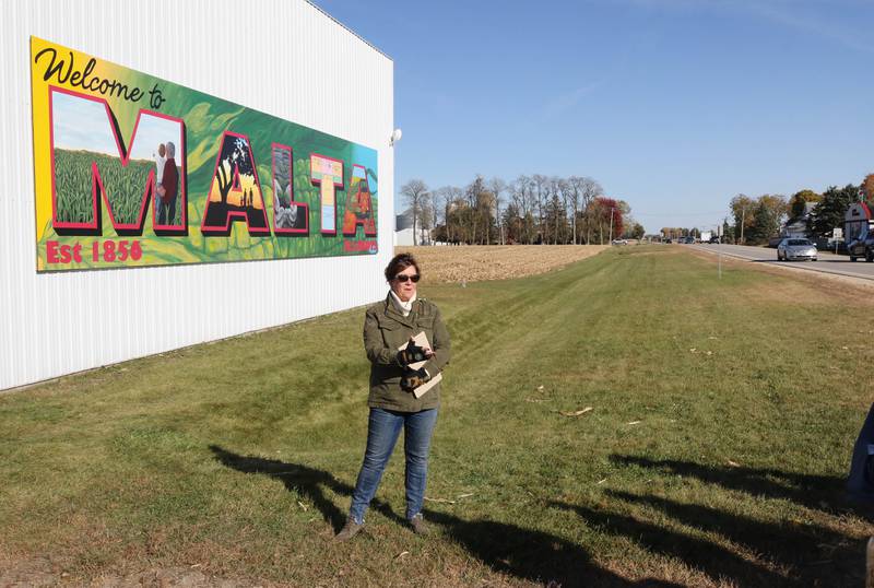 Jacque Fucilla, a member of the Malta Seedling Committee, talks about the new mural by Dixon artist Nora Balayti before the official ribbon cutting Wednesday, Oct. 19, 2022, on the north side of Route 38 in Malta. The mural, which spells out Malta in large capital letters, depicts the values of the town with themes of agriculture, family, community and growth.