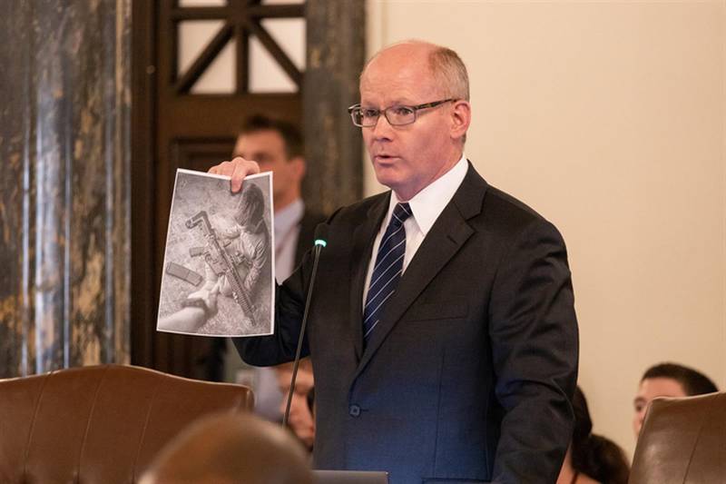 Senate President Don Harmon, D-Oak Park, holds up an ad from the company Wee 1 Tactical, maker of the JR-15 rifle, a gun that resembles an AR-15 rifle but is smaller and lighter, making it easier for children to fire. He showed the photo during debate on a bill that places limits on how gun manufacturers and retailers can market their products.