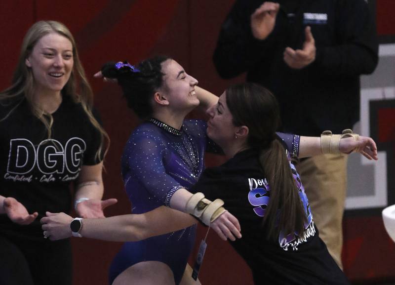Downers Grove's Genevieve Herion celebrates with her coaches after competing  in the preliminary round of the balance beam on Friday, Feb. 21, 2025, during the IHSA Girls State Final Gymnastics Meet at Palatine High School.