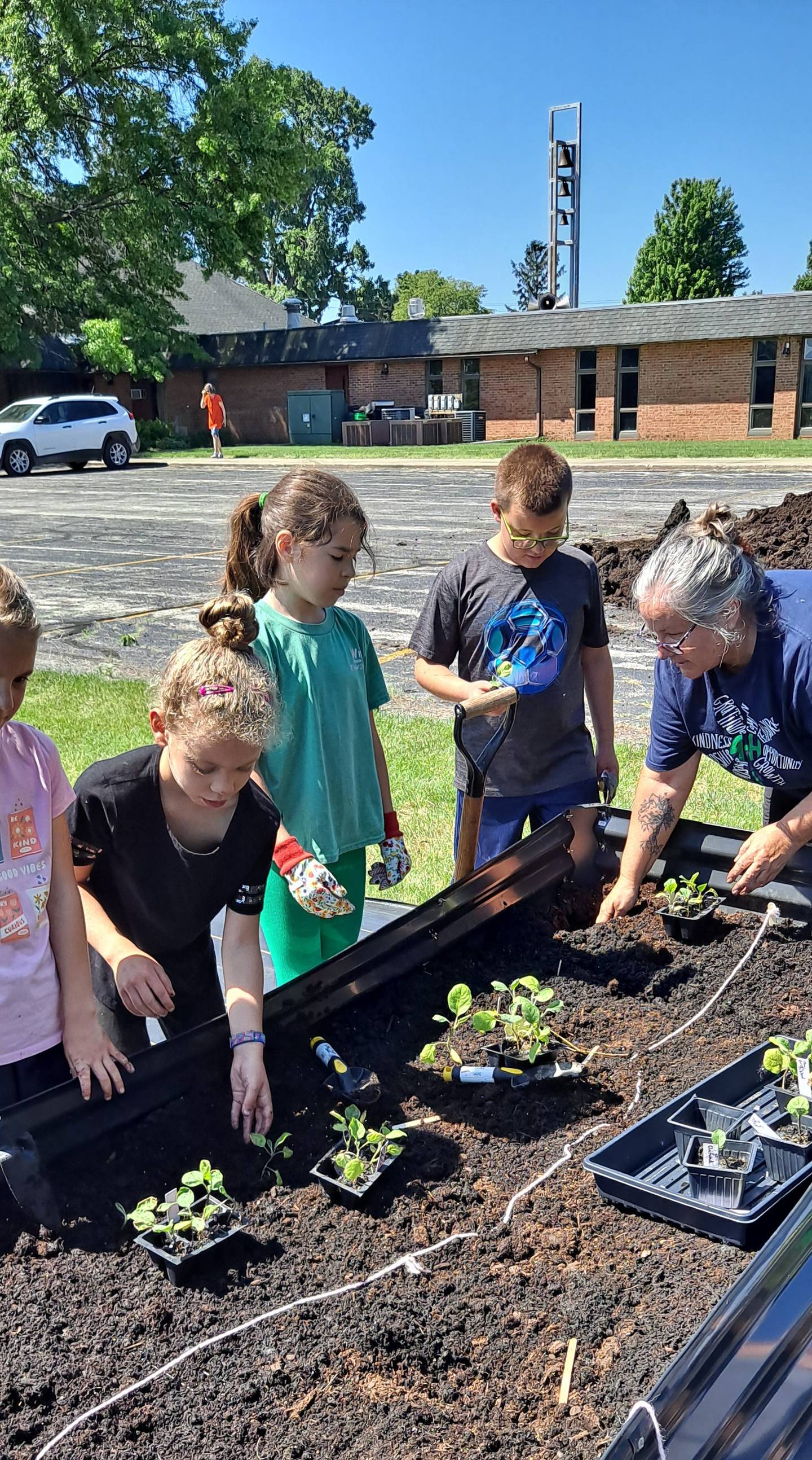 Marshall-Putnam 4-H members plant seedlings at Henry Methodist Church with Master Gardener coordinator Bettyann Harrison (right).