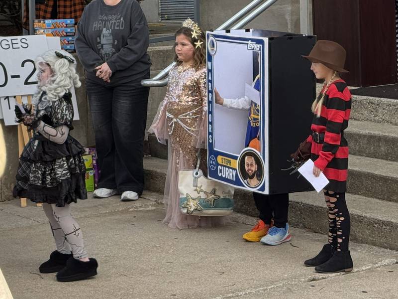 The Broken Doll (left), a mermaid, a Stephen Curry basketball card, and Freddy Krueger all take their prizes during the Lions Club Costume Contest on Thursday, Oct. 30, 2025.