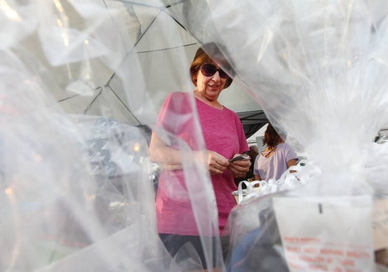 Nancy Guenther, of Lake Villa with Wilmot Heritage Antiques, puts her tickets into buckets to try and win a raffle prize during the final concert of the "It’s Thursday” summer concert series on August 10th in Antioch. The event and its proceeds were dedicated to Huntley, a child who was injured during the Taste of Summer in July. 
Photo by Candace H. Johnson for Shaw Local News Network