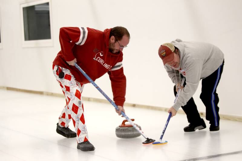 Sweepers Matt Galas of Glen Ellyn and Scott Gerstenkorn participate in a drop-in game of Curling at the Windy City Curling Club in Villa Park.